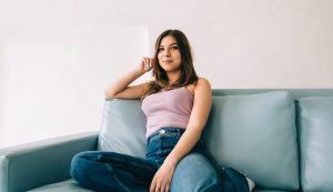 hopeful hispanic young woman sitting on a couch