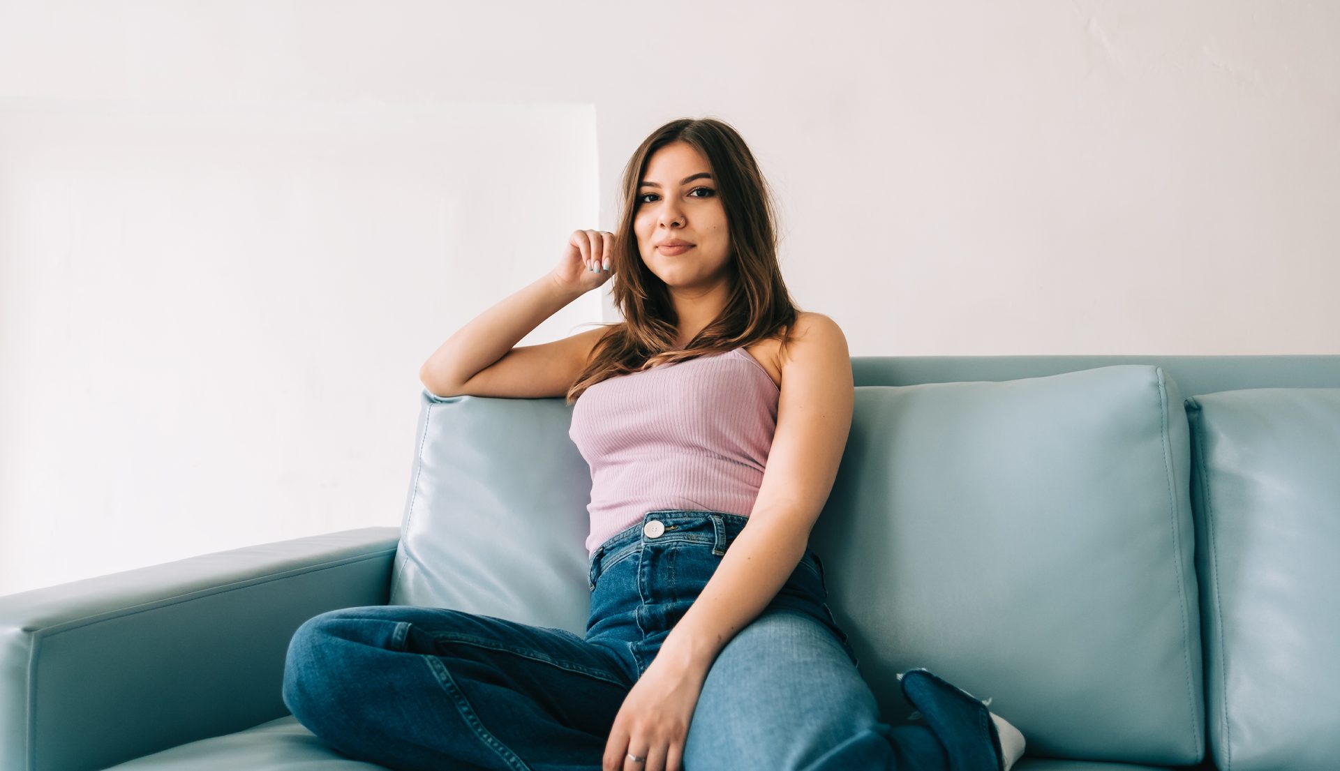 hopeful hispanic young woman sitting on a couch